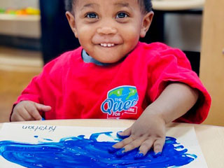 Young boy creates art through sensory play and paint. Process art stimulates sensory exploration.