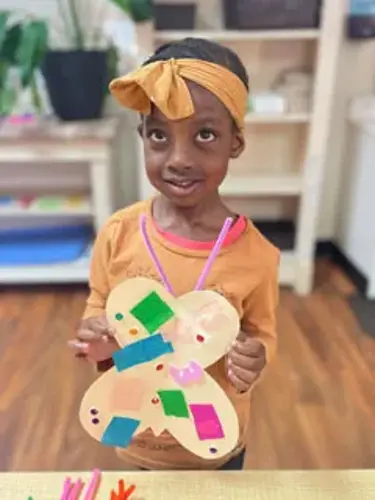 little girl making butterfly art at daycare